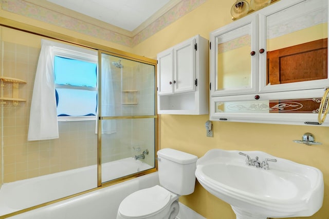 full bathroom with sink, bath / shower combo with glass door, and toilet