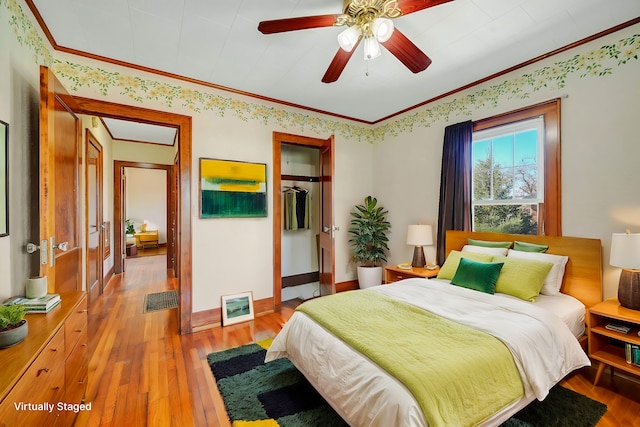 bedroom with a closet, ceiling fan, hardwood / wood-style floors, and ornamental molding