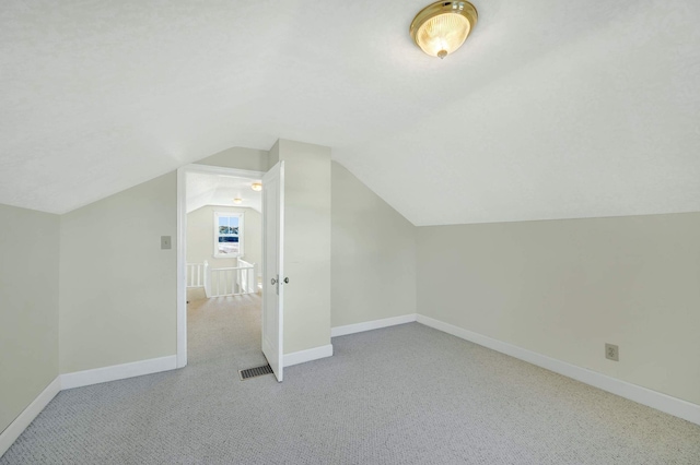 bonus room with light colored carpet and lofted ceiling