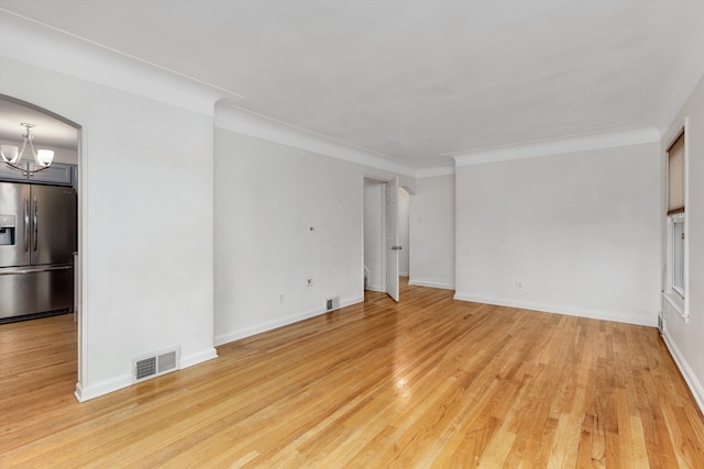 unfurnished living room featuring crown molding, a chandelier, and light hardwood / wood-style flooring