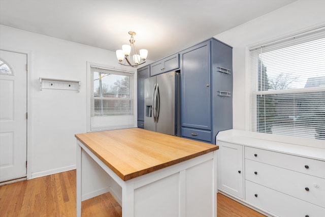 kitchen with pendant lighting, butcher block countertops, stainless steel refrigerator with ice dispenser, light hardwood / wood-style floors, and a chandelier