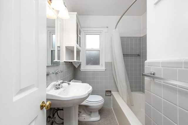 bathroom with toilet, tile patterned flooring, tile walls, and shower / bath combo