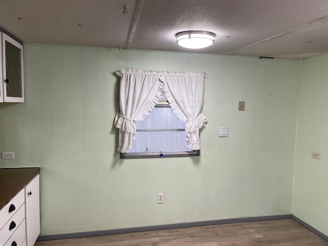 spare room with wood walls, light hardwood / wood-style floors, and a textured ceiling