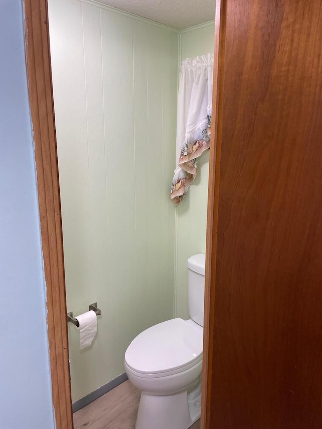 bathroom with hardwood / wood-style floors, toilet, and a textured ceiling