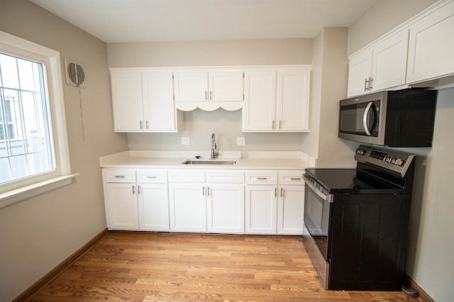 kitchen featuring sink, white cabinetry, stainless steel appliances, and light hardwood / wood-style flooring