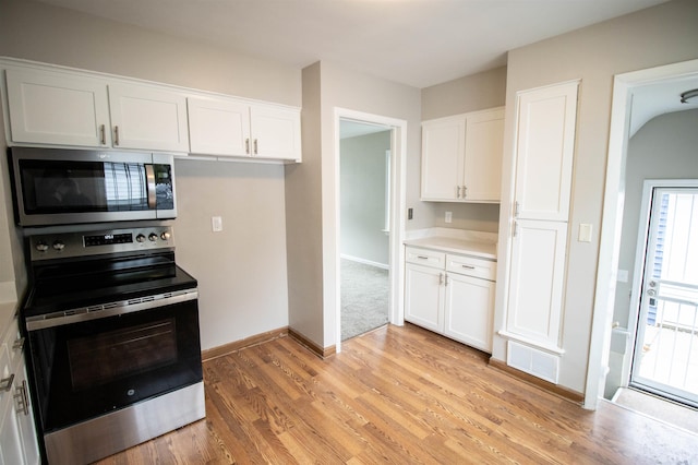 kitchen with appliances with stainless steel finishes, light hardwood / wood-style flooring, and white cabinetry