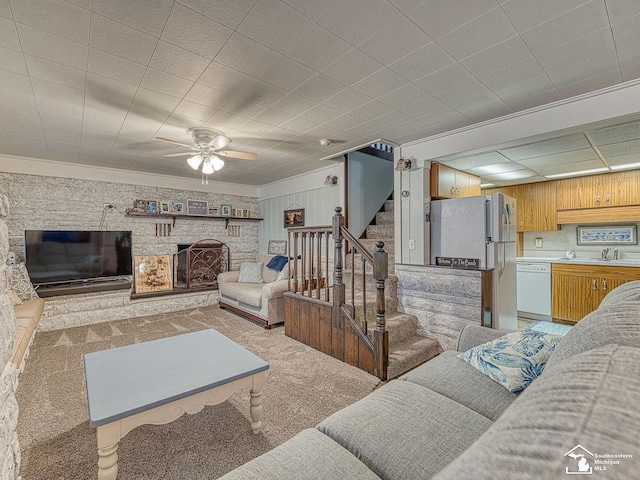 11477 Highland Hills Dr, Jerome, MI 49249 - living area with light carpet, stairs, ceiling fan, a fireplace with raised hearth, and crown molding