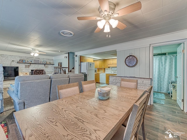11477 Highland Hills Dr, Jerome, MI 49249 - dining space featuring ceiling fan, wood finished floors, and a fireplace