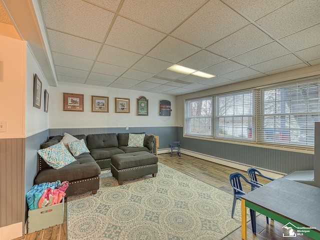 11477 Highland Hills Dr, Jerome, MI 49249 - living area featuring wood finished floors, a wainscoted wall, a drop ceiling, and a baseboard heating unit