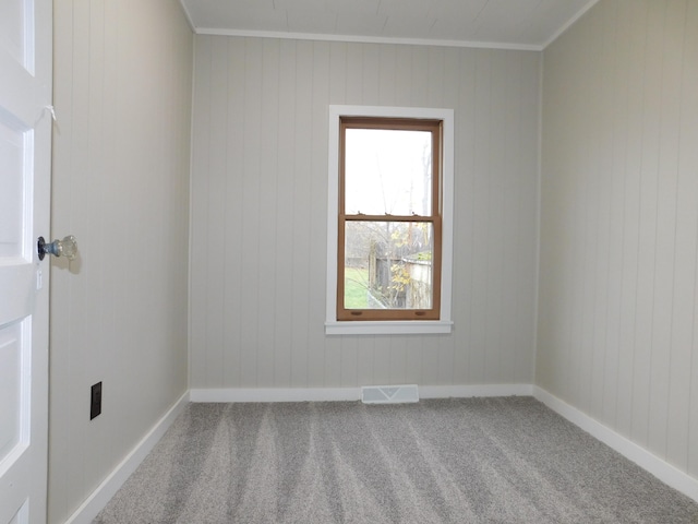 unfurnished room featuring carpet floors, ornamental molding, and wood walls