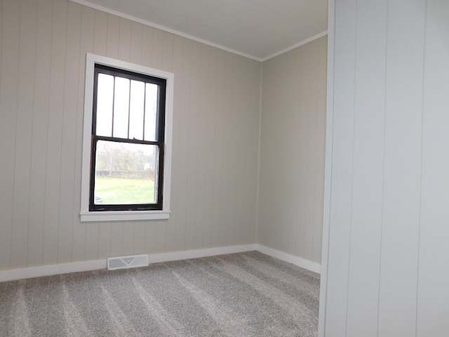 carpeted empty room featuring wooden walls and crown molding