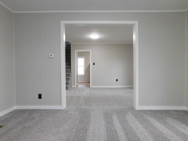 carpeted empty room with wooden walls and ornamental molding