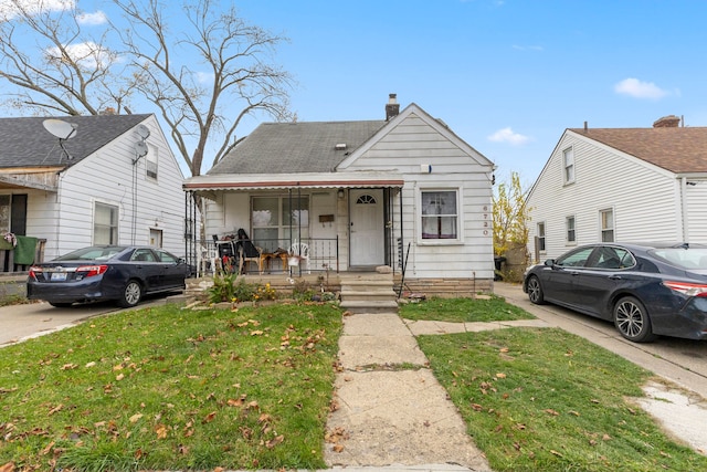 bungalow-style home with a front lawn and covered porch