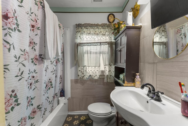 full bathroom with shower / bath combo with shower curtain, sink, tile walls, and toilet