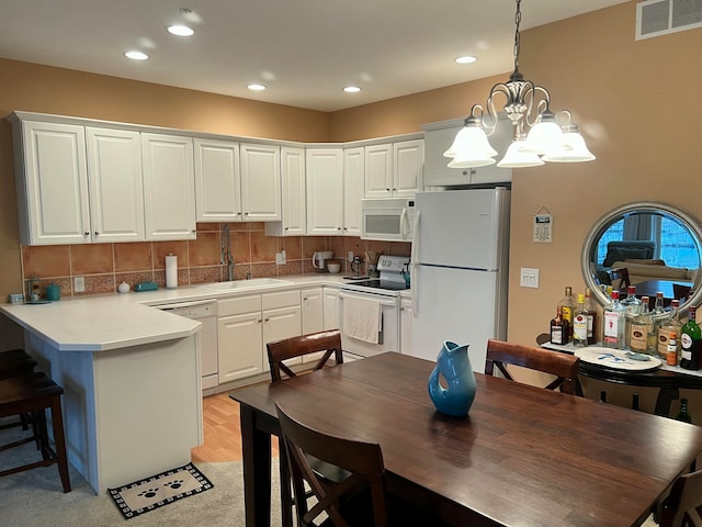 kitchen with sink, an inviting chandelier, pendant lighting, white appliances, and white cabinets