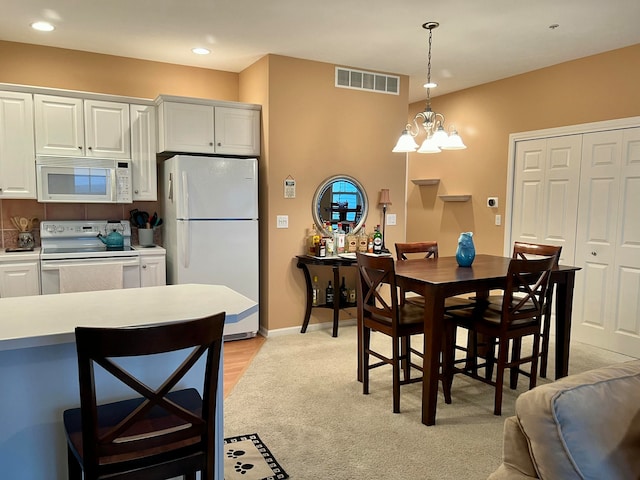 carpeted dining area with a chandelier