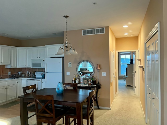 carpeted dining area featuring a healthy amount of sunlight, sink, and a chandelier