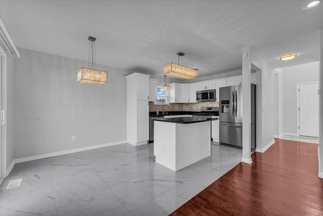 kitchen with white cabinets, stainless steel appliances, a kitchen island, and hanging light fixtures