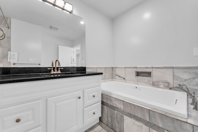 bathroom featuring tile patterned flooring, vanity, and a relaxing tiled tub