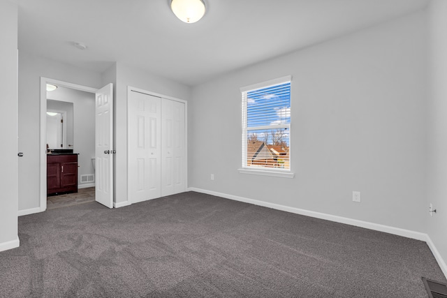 unfurnished bedroom with a closet and dark colored carpet