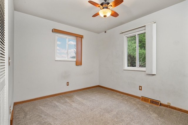 unfurnished room featuring a wealth of natural light, carpet floors, and ceiling fan