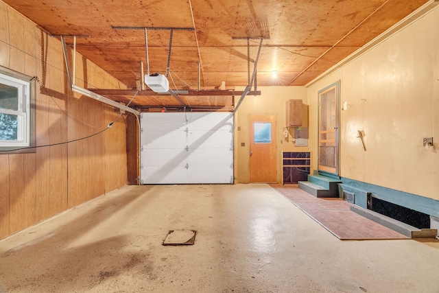 garage featuring a garage door opener, wooden walls, and wooden ceiling