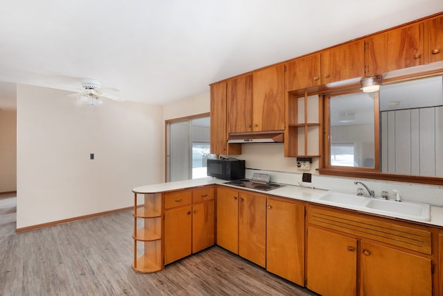 kitchen with kitchen peninsula, light wood-type flooring, ceiling fan, and sink