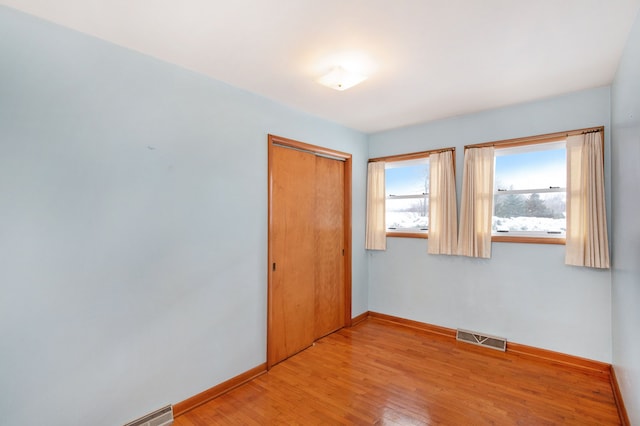 unfurnished bedroom with light hardwood / wood-style flooring and a closet