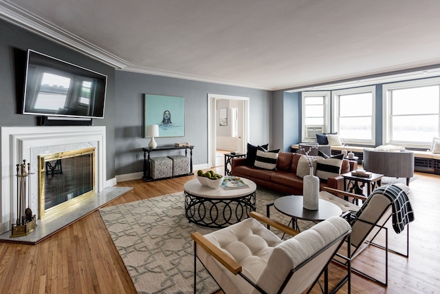 living room with a high end fireplace, ornamental molding, and light wood-type flooring