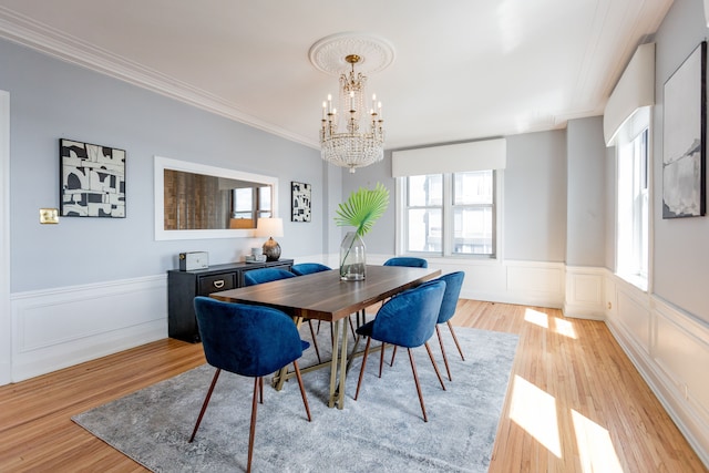 dining space with a chandelier, light wood-type flooring, and crown molding