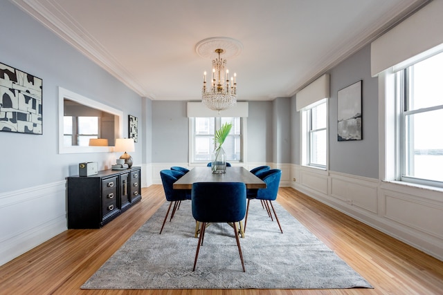 dining space featuring an inviting chandelier, light hardwood / wood-style flooring, and ornamental molding