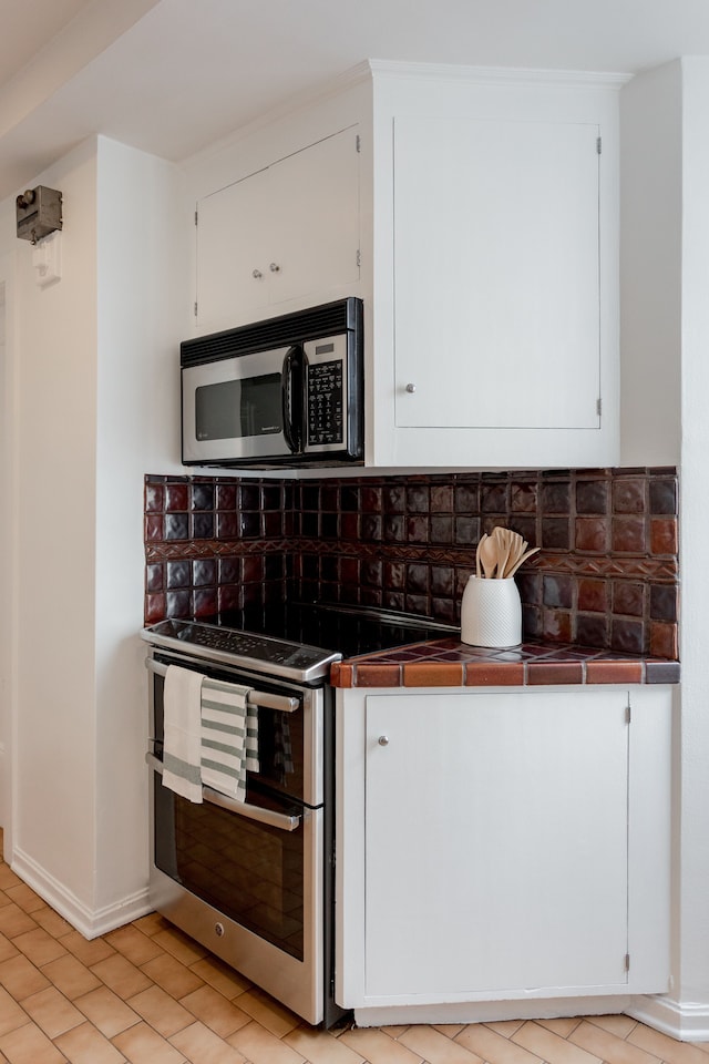 kitchen featuring tasteful backsplash, stainless steel appliances, white cabinetry, and tile counters