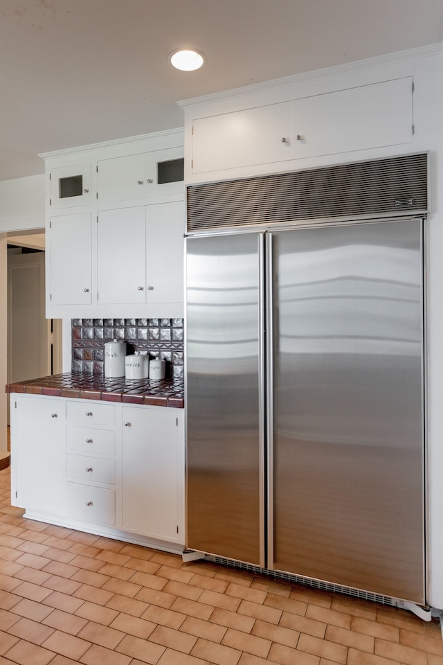 kitchen featuring decorative backsplash, stainless steel built in fridge, and white cabinets