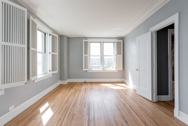 spare room featuring plenty of natural light, light hardwood / wood-style floors, and crown molding