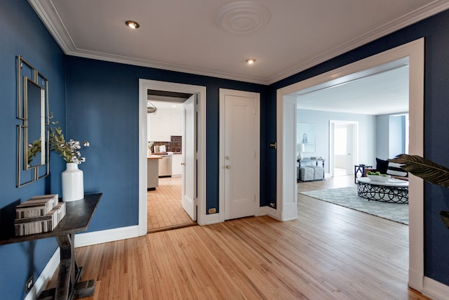 corridor with light hardwood / wood-style floors and crown molding