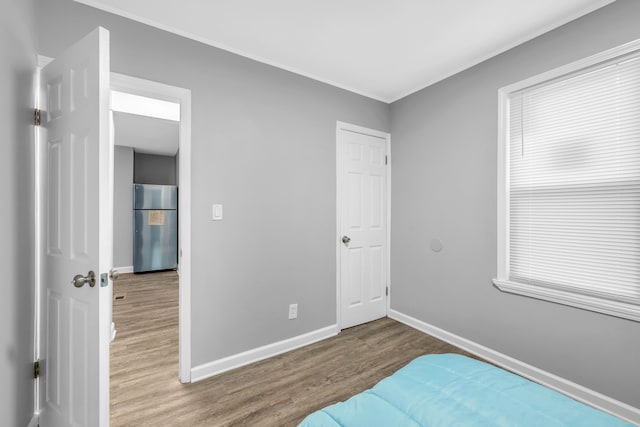 bedroom featuring crown molding, hardwood / wood-style floors, and stainless steel refrigerator