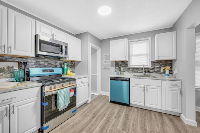 kitchen featuring appliances with stainless steel finishes, sink, light hardwood / wood-style flooring, and white cabinets