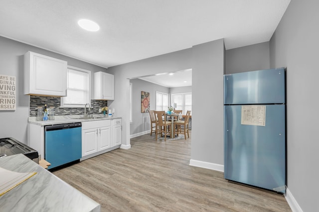 kitchen featuring sink, white cabinetry, tasteful backsplash, appliances with stainless steel finishes, and light hardwood / wood-style floors