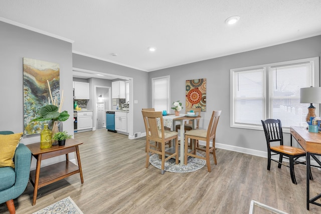 dining room featuring crown molding, light hardwood / wood-style flooring, and a textured ceiling