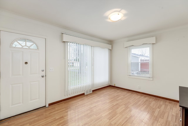 entryway with light hardwood / wood-style floors, an AC wall unit, and crown molding