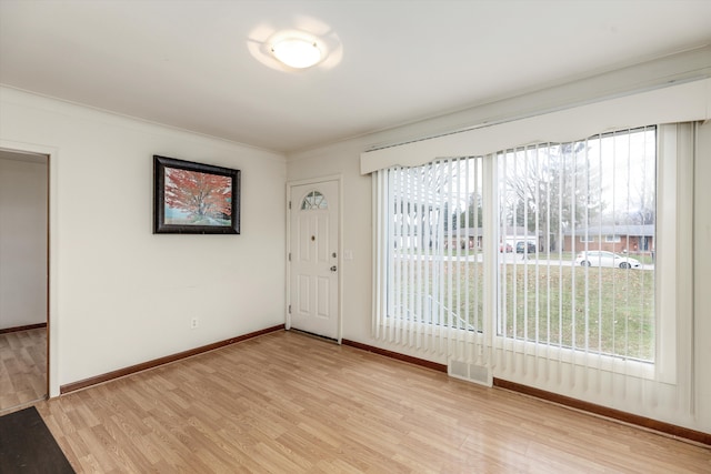 unfurnished room with plenty of natural light, crown molding, and light hardwood / wood-style flooring