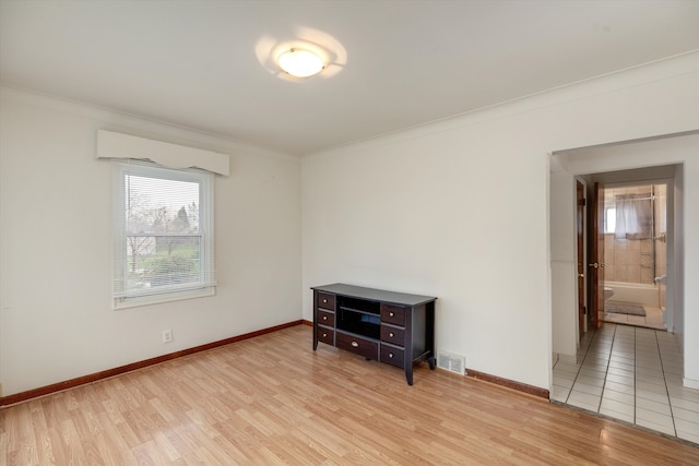 empty room featuring a wall mounted air conditioner, crown molding, and light wood-type flooring