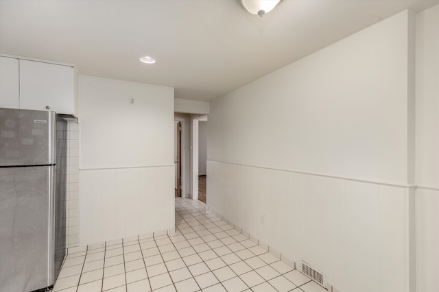 kitchen featuring white cabinets, stainless steel fridge, and light tile patterned flooring