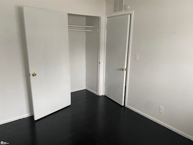 unfurnished bedroom featuring dark hardwood / wood-style flooring and a closet