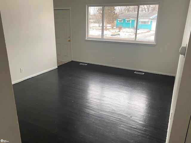 empty room featuring plenty of natural light and dark wood-type flooring