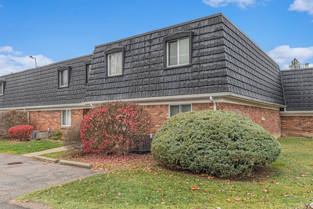 view of side of property featuring a lawn and central AC