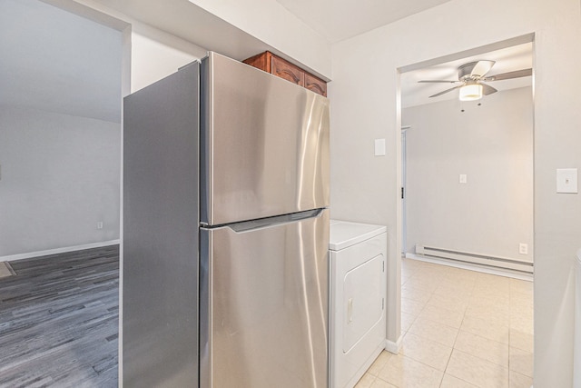 kitchen featuring ceiling fan, baseboard heating, light hardwood / wood-style flooring, washer / clothes dryer, and stainless steel refrigerator