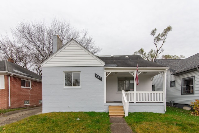 bungalow with covered porch and a front lawn