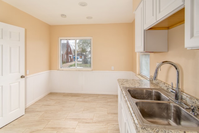 kitchen featuring light stone countertops, sink, and white cabinets