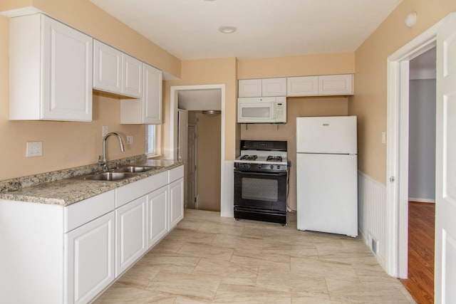 kitchen featuring white cabinets, white appliances, light stone counters, and sink